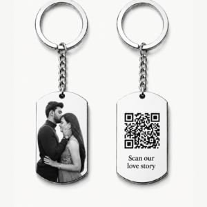 Hidden Message Photo Keychain: Two silver keychains displayed on a clean light background. One rectangular pendant features a black-and-white couple photo, and the other pendant shows a QR code with the words “Scan our love story.