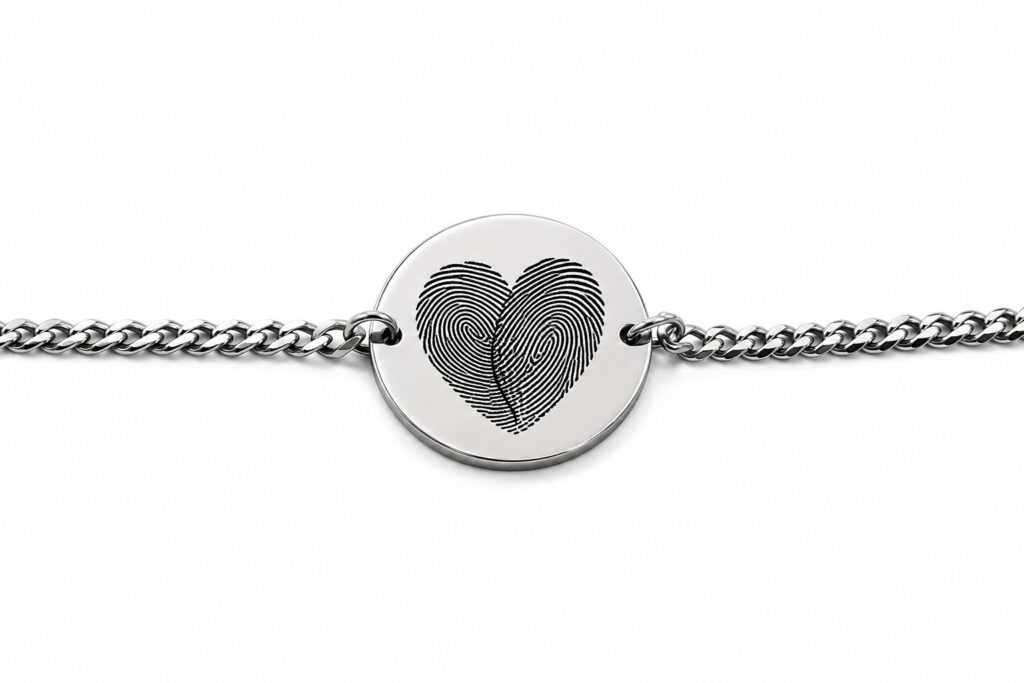 Close-up of a silver fingerprint disc bracelet showing two fingerprints engraved together as a heart. Custom thumbprint bracelet detail, engraved to order from your own fingerprint photos.
