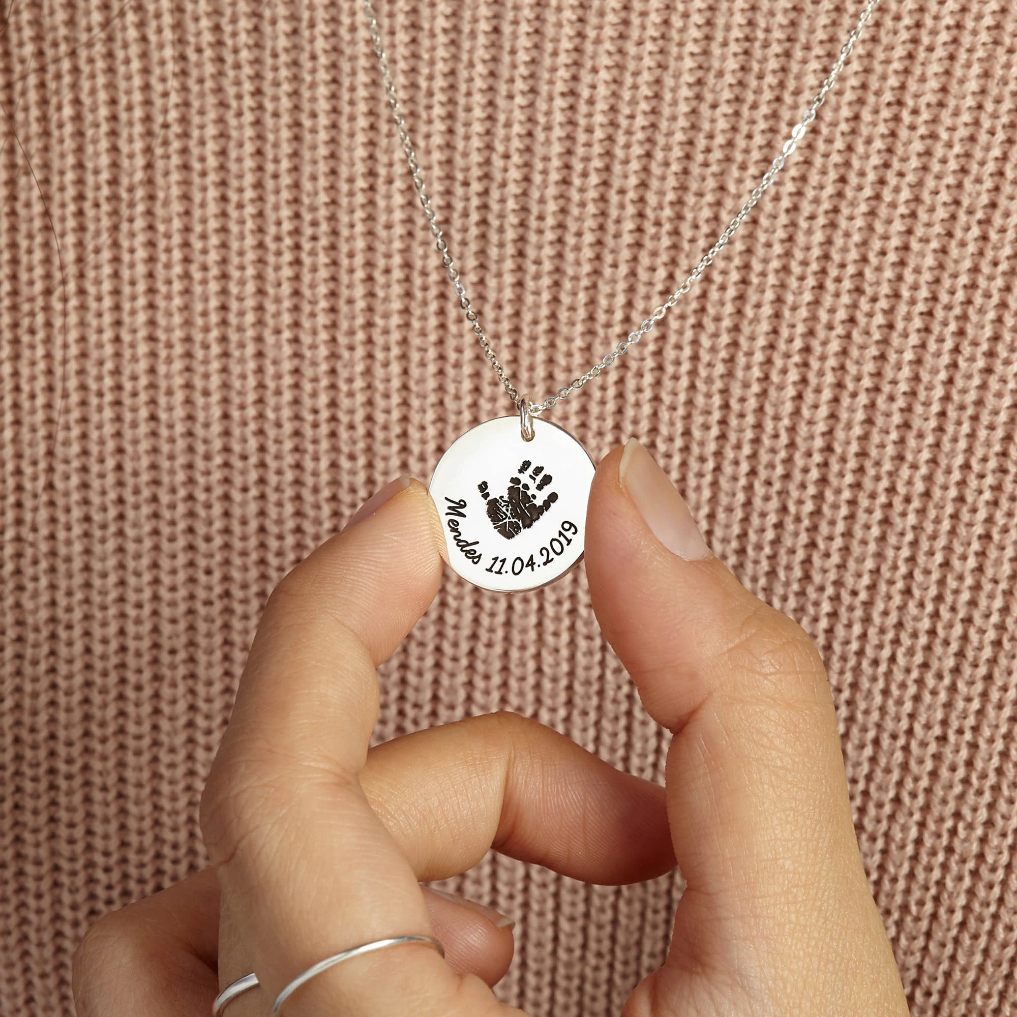 Mother wearing engraved baby handprint necklace as sentimental keepsake