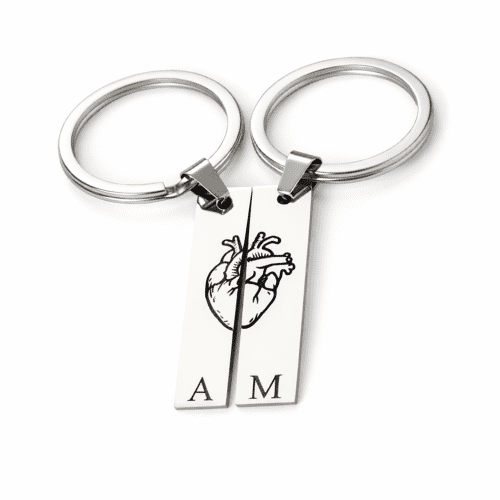 Two matching split heart keychains engraved with initials, placed together to form a complete heart.